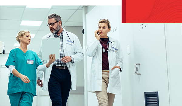 Three medical professionals walking down hospital hallway.