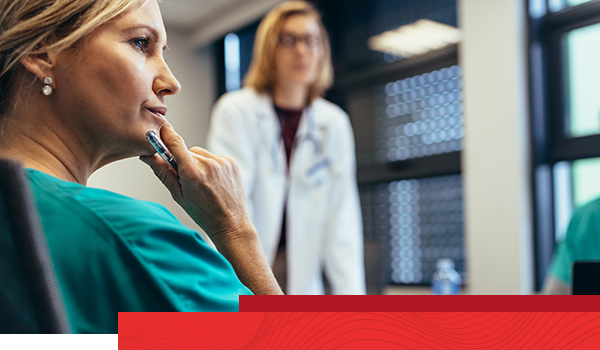 Attentive female medical professional strategizes with coworkers.